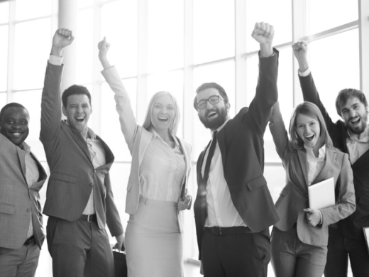 Group of ecstatic business partners looking at camera with raised arms